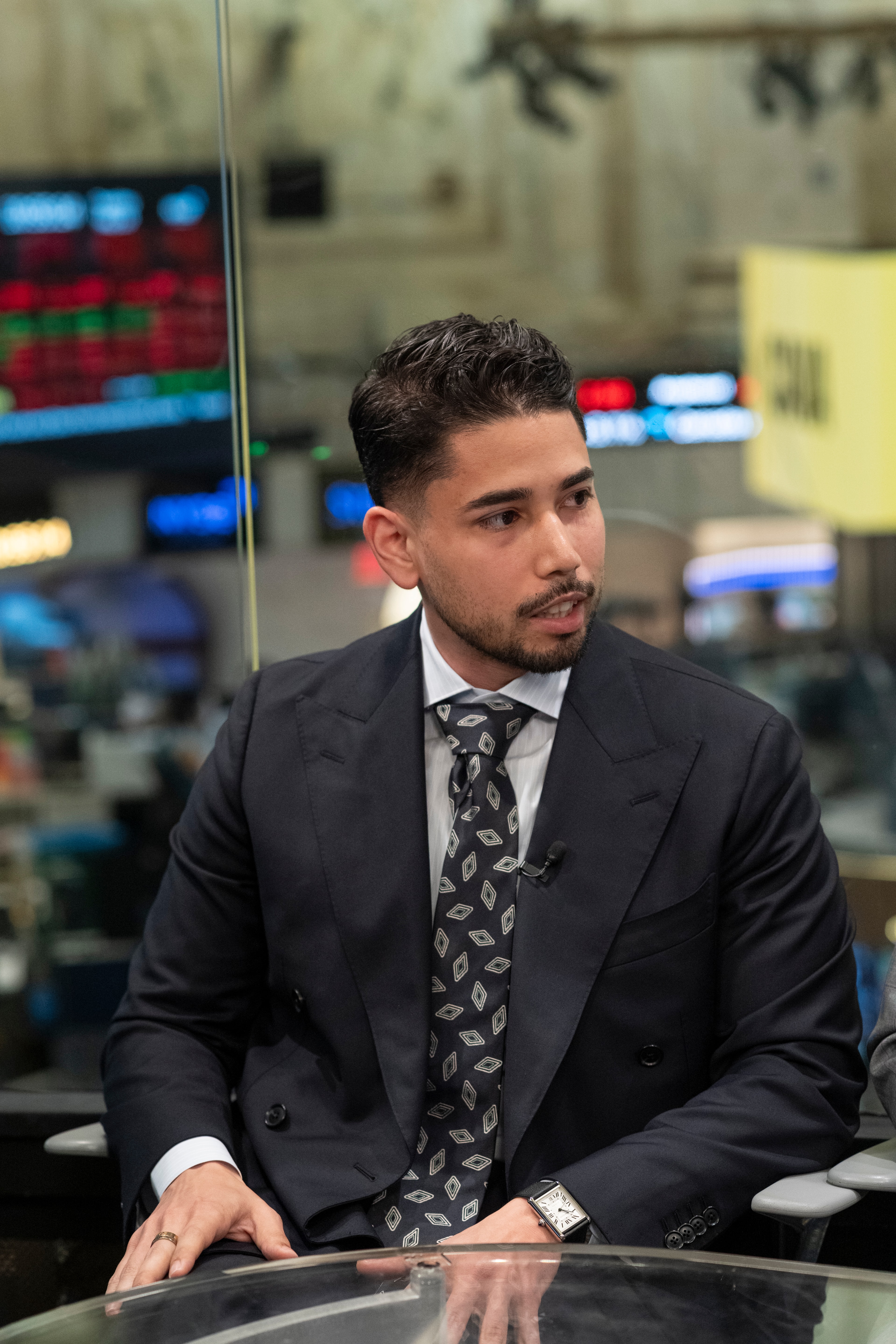 Omar Hafez seated at the broadcast desk on the New York Stock Exchange floor