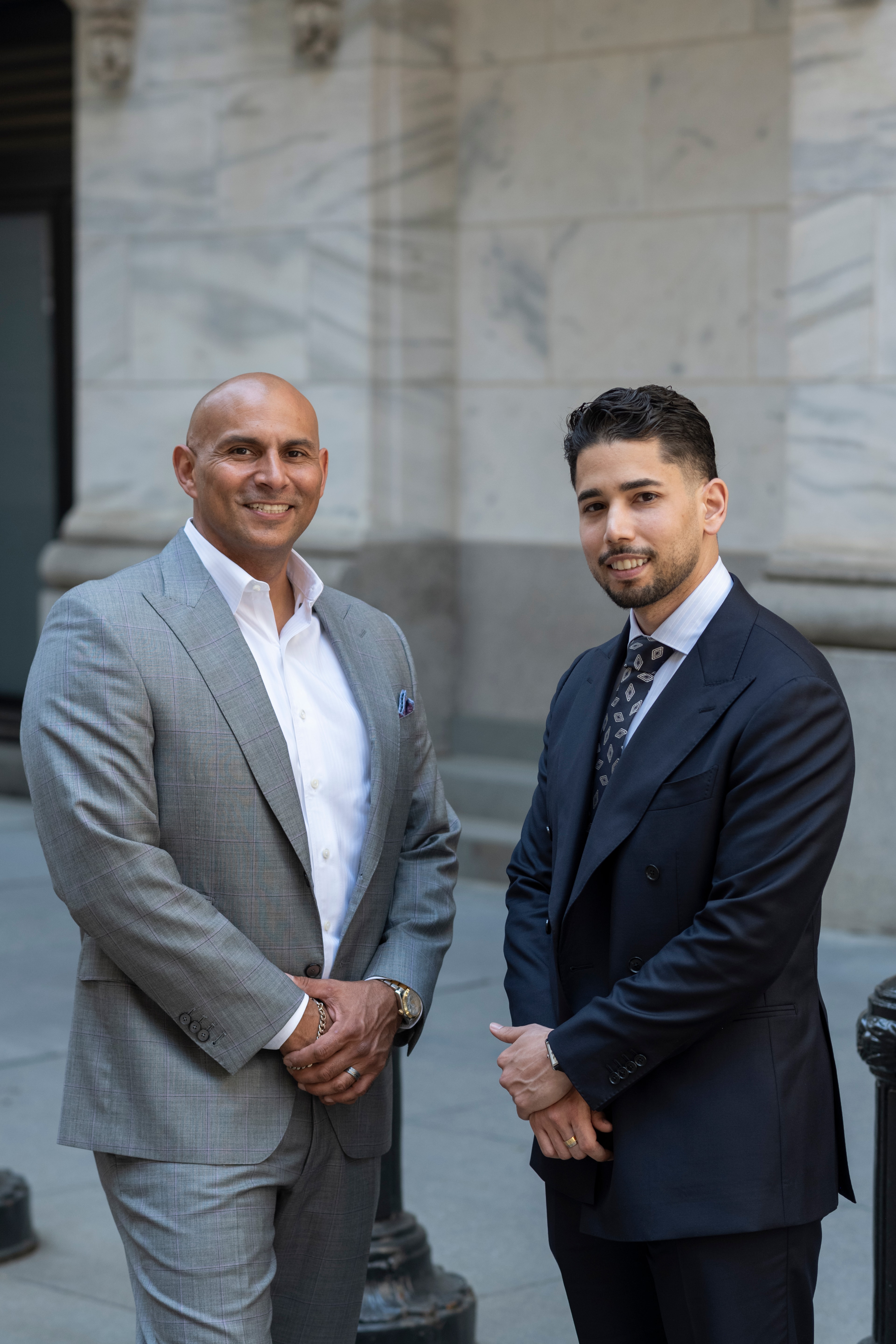 Omar Hafez and a colleague standing outside the columned entrance of the New York Stock Exchange