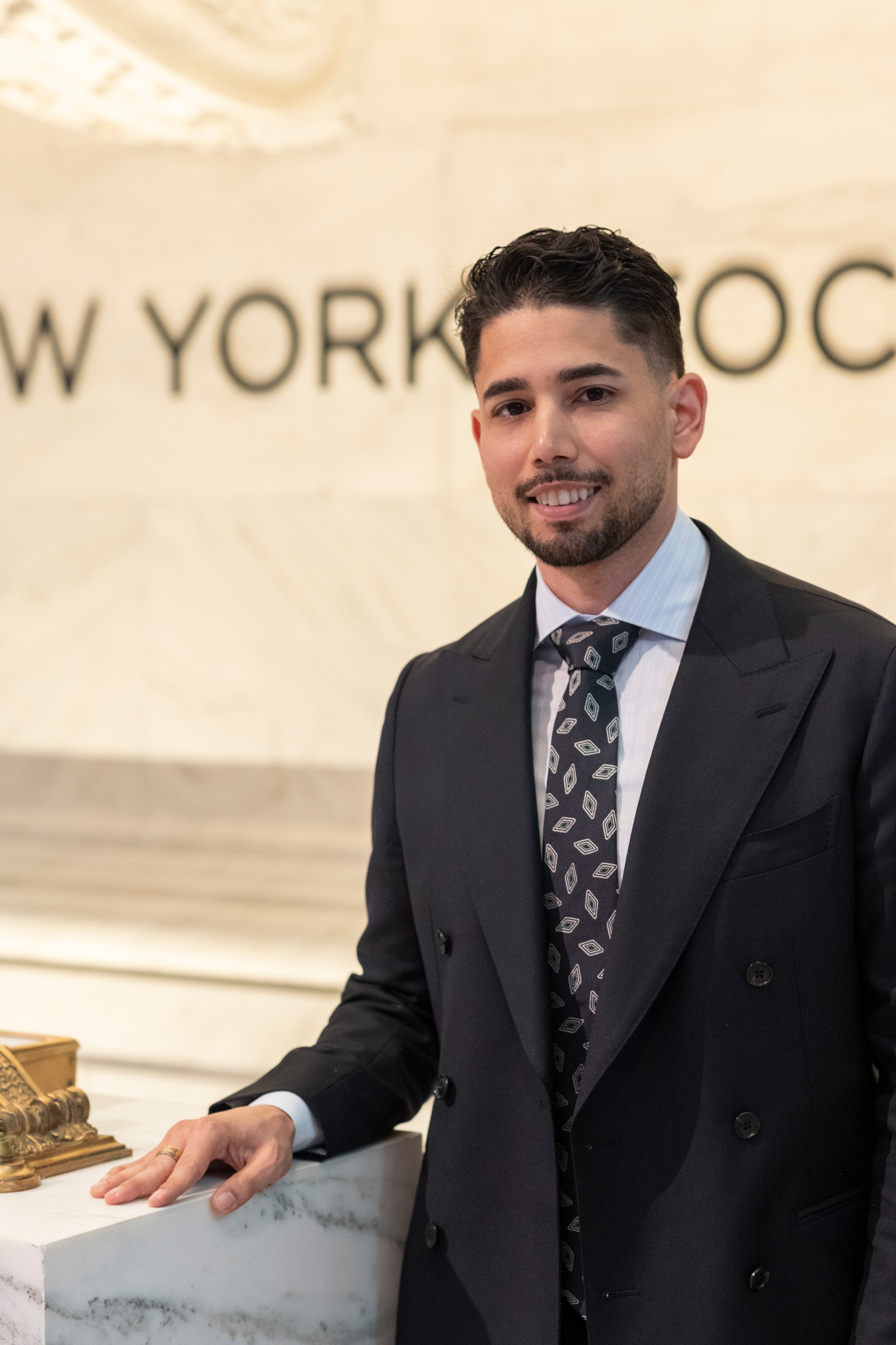 Omar Hafez beside the marble wall of the New York Stock Exchange lobby