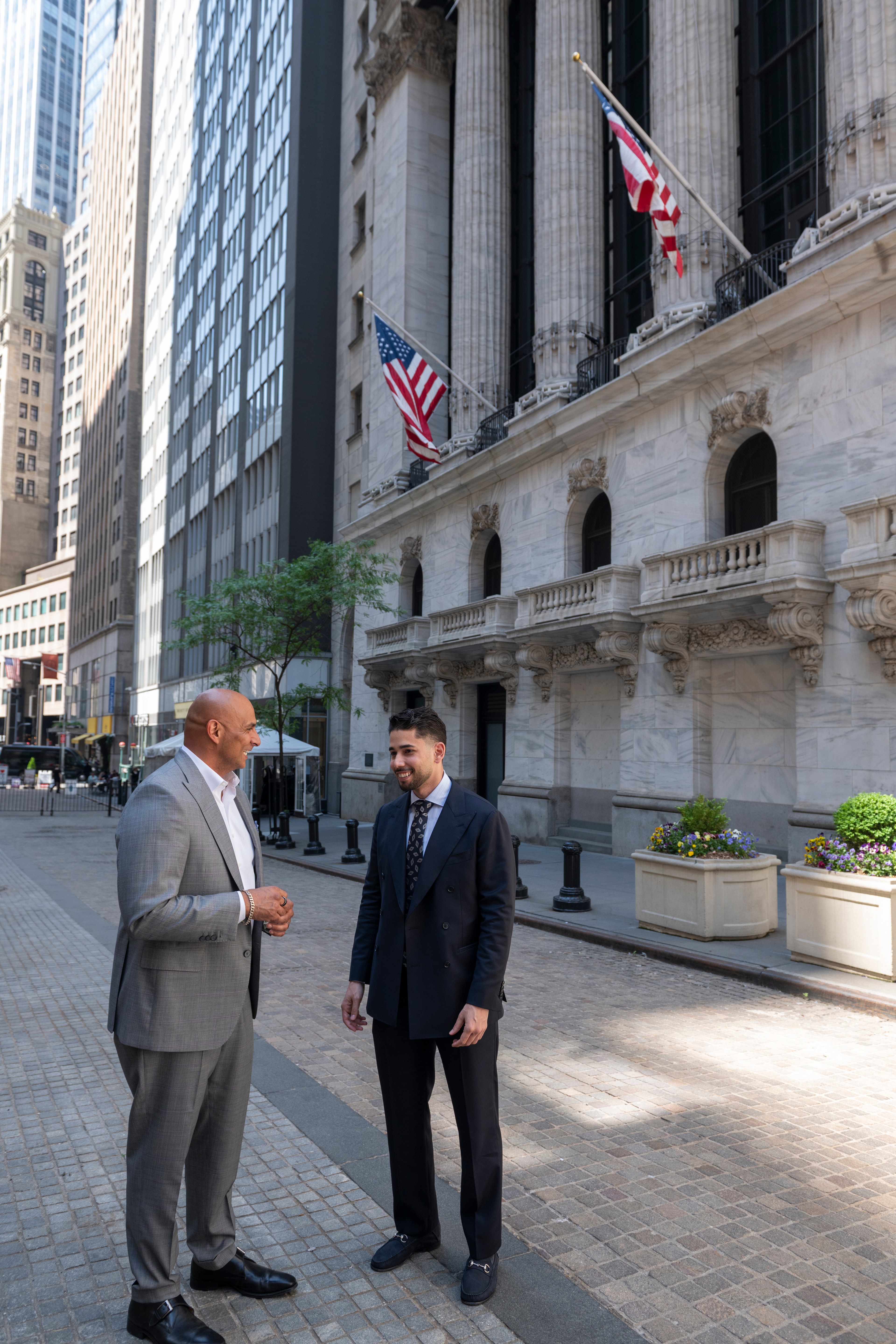 Omar Hafez and a colleague talking on the sidewalk outside the New York Stock Exchange